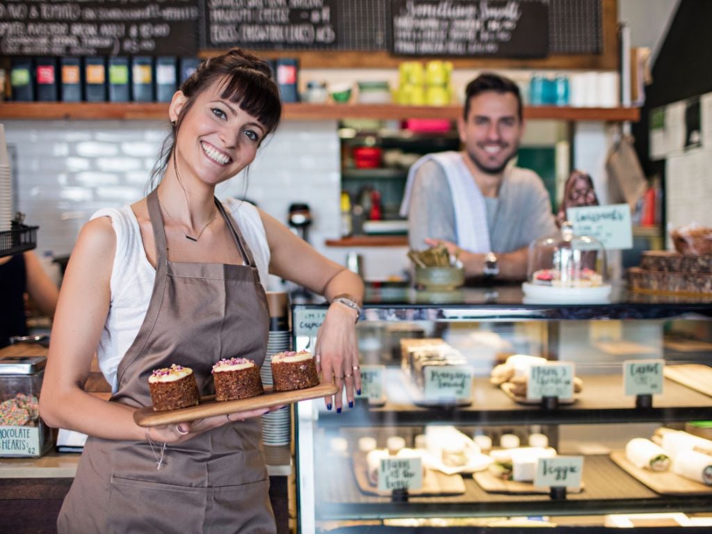 woman smiling holding baked goods at a cafe