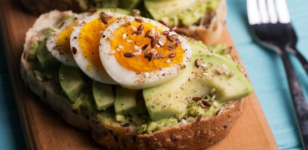 Eggs on Toasts with avocado on a wooden board 