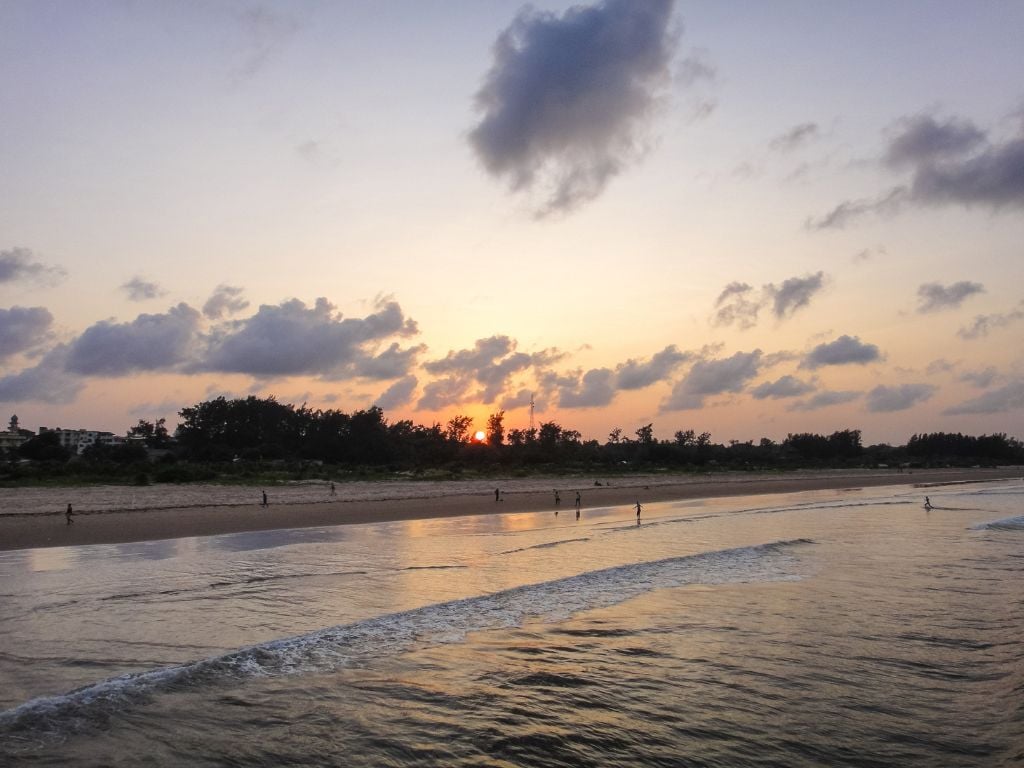 sun setting behind the beach with people on the sand