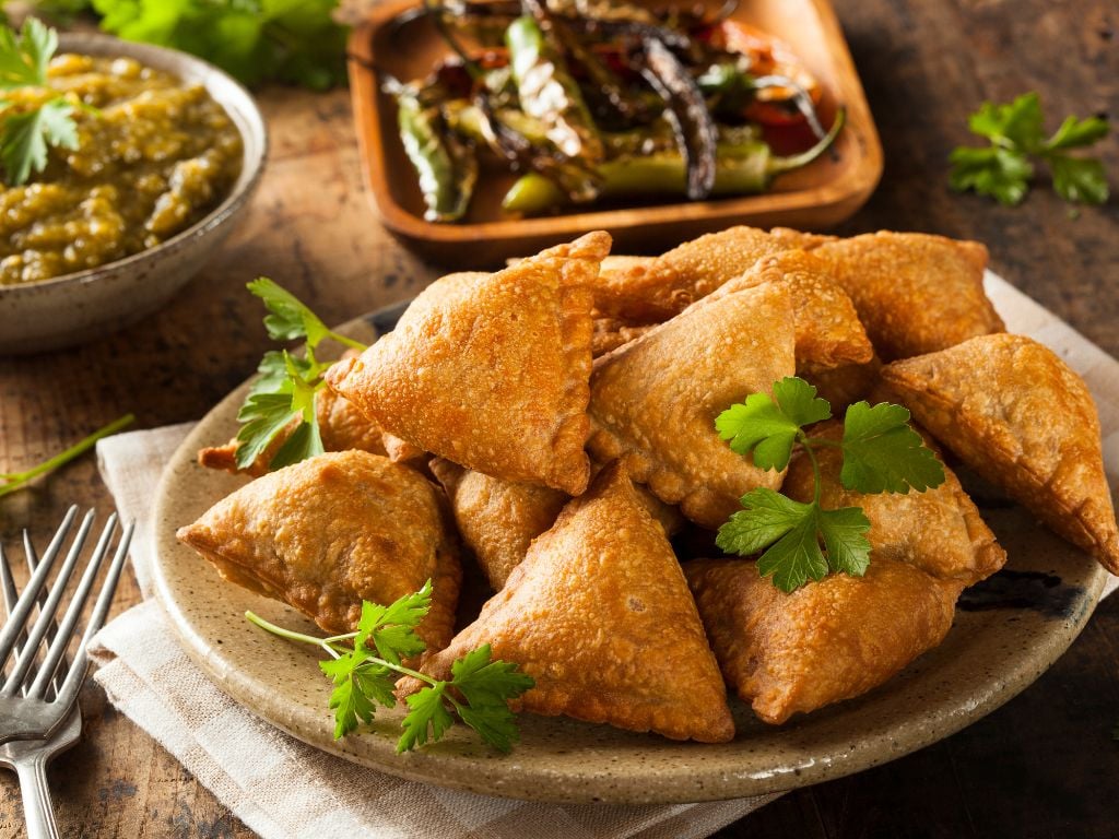 samosas on a plate with some peppers and sauce next to it