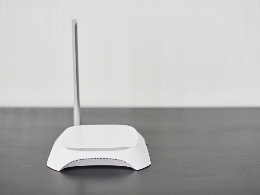 white wifi router on a table with one antenna