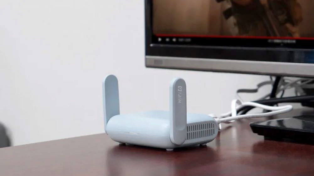 a travel router sitting on a desk with a computer