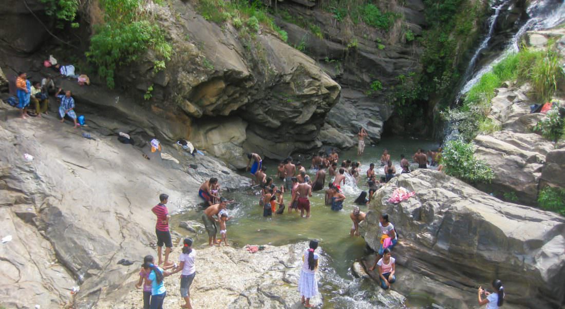 people bathing at a waterfall in sri lanka