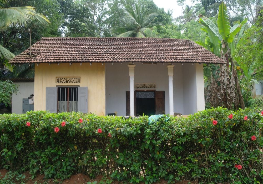 small house with tiled roof and green bushes out front