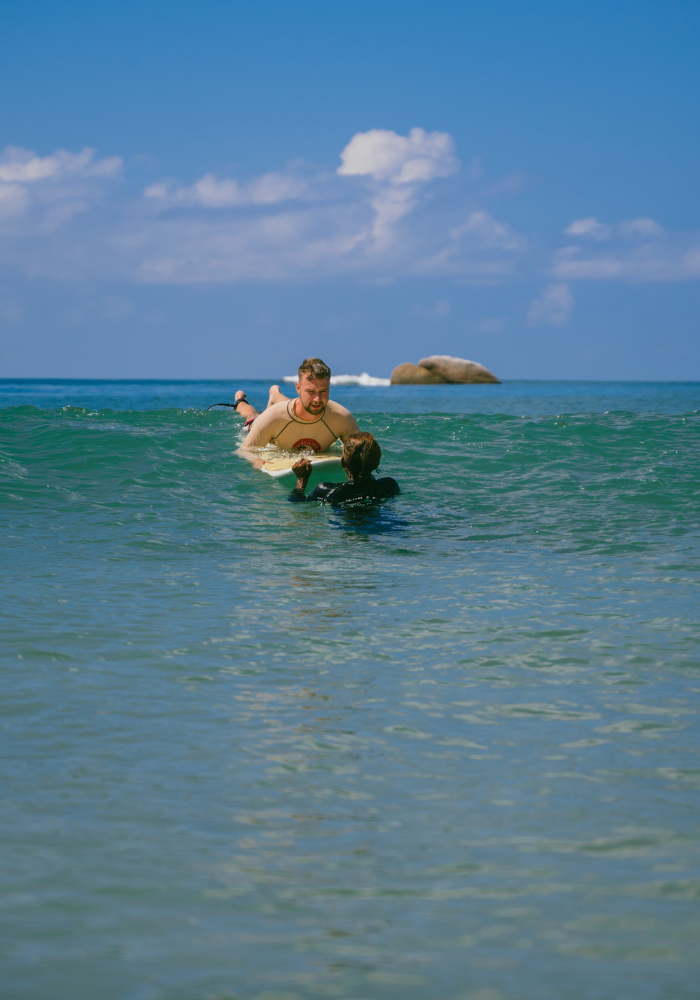 man learning how to surf in the sea in sri lanka