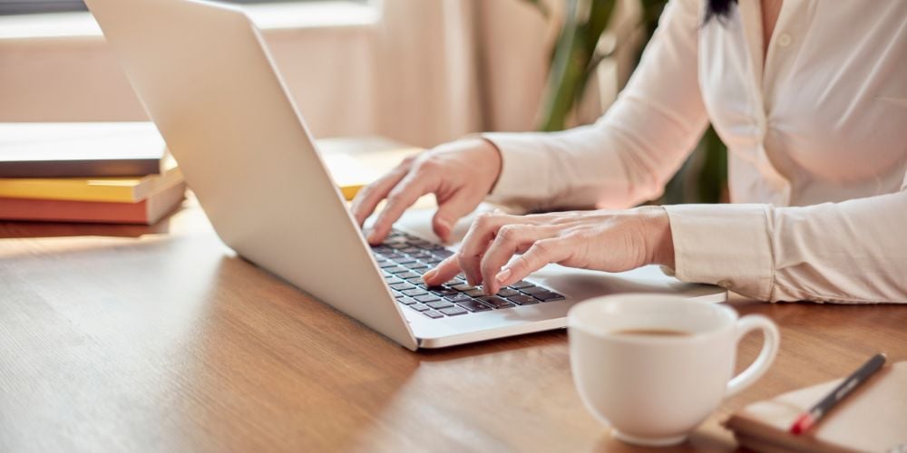 woman working as a freelancer on her laptop with a coffee cup