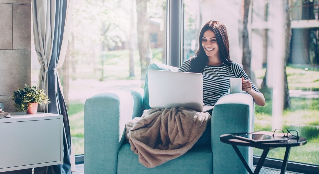 woman sitting on the couch with her laptop and blanket