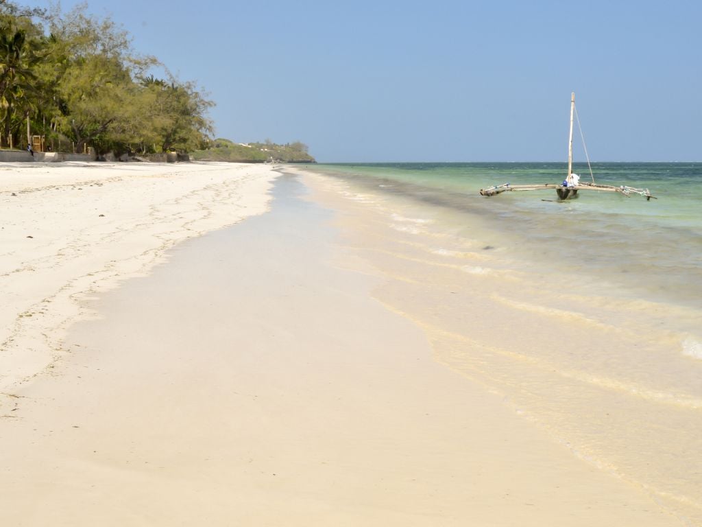 bamburi beach with white sand and a boat floating in the water
