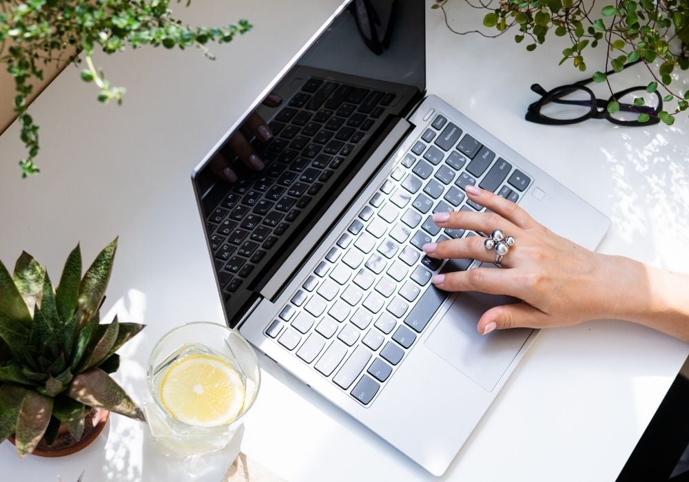 how to become a freelance writer with no experience woman at a desk with a computer and a drink