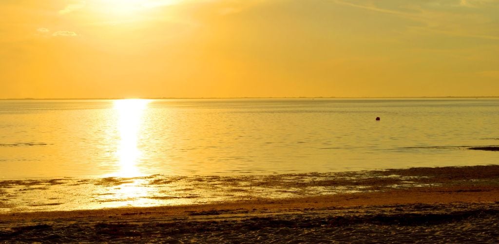 Ben T. Davis Beach- a setting sun with rays reflecting the ocean