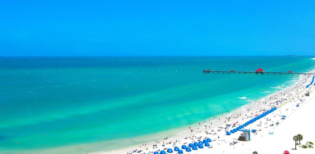 Clearwater Beach- A wide body of ocean with blue tents on the side
