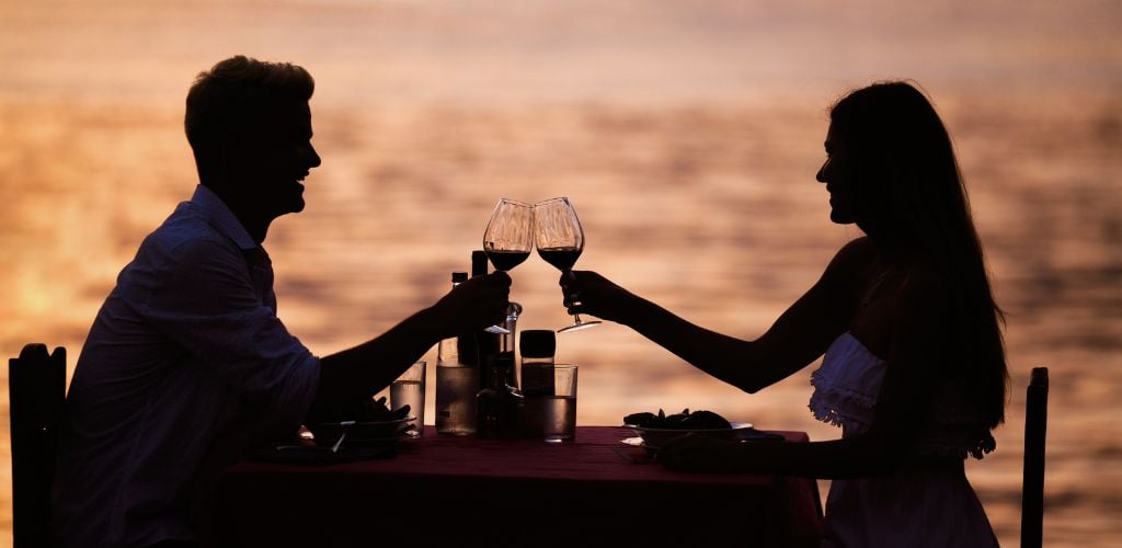 a silhouette picture of romantic couple having a wine drink