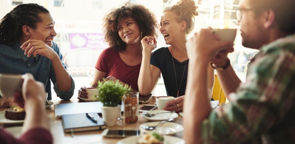 A group of people enjoying and laughing while drinking coffee.