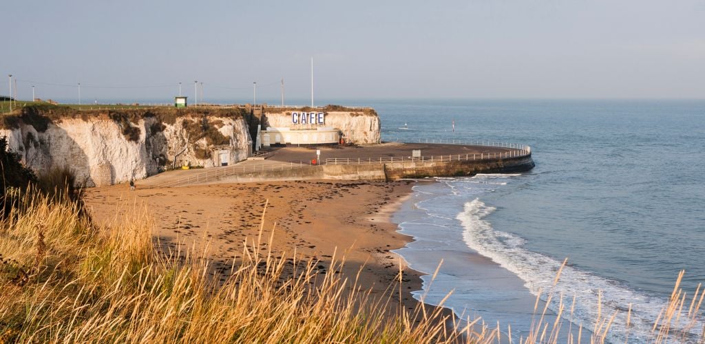 Margate to Broadstairs A cliff beside the ocean with rounding fences and grasses