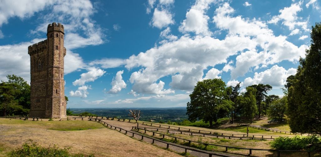 Leith Hill (Surrey) small fences along dirt road with tower and trees along the blue sky