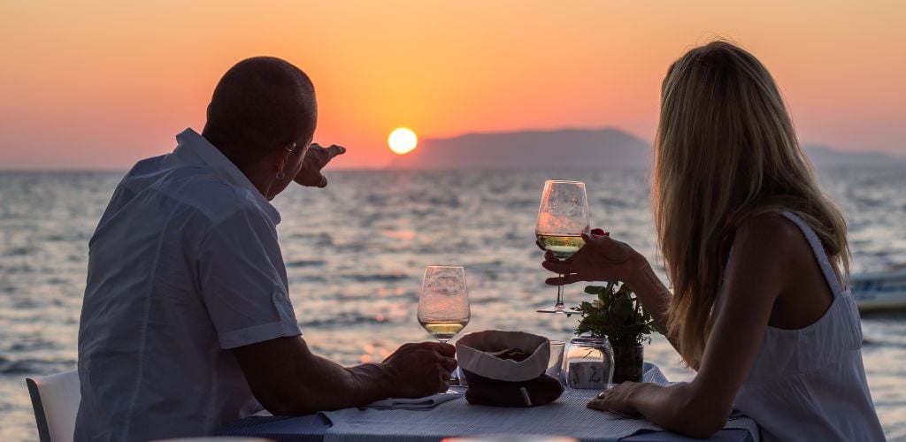 A couple having a dinner on the beach while sunset.