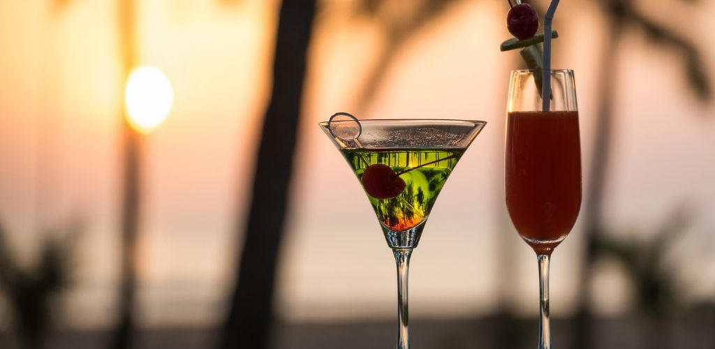 Two cocktails with palm trees and sunset. 