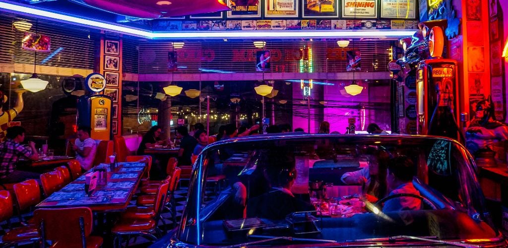 A dark American diner with people seated at tables.