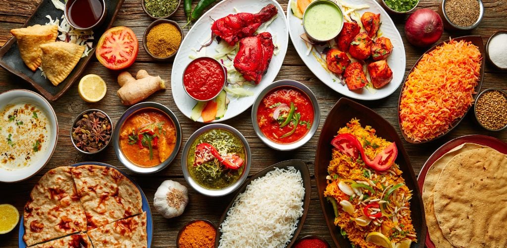 Assorted breakfast with bread, rice, meat and spices on a wooden table.