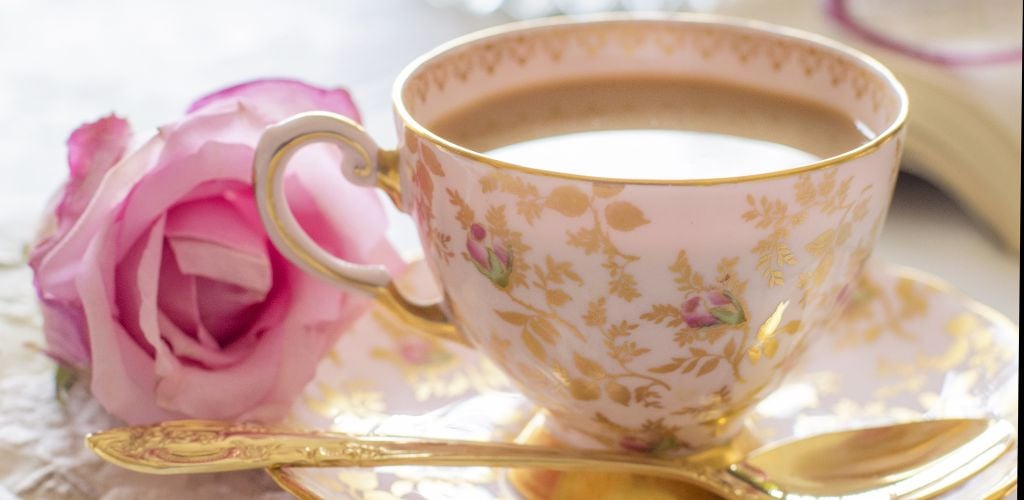 A cup of milky tea with pink rose