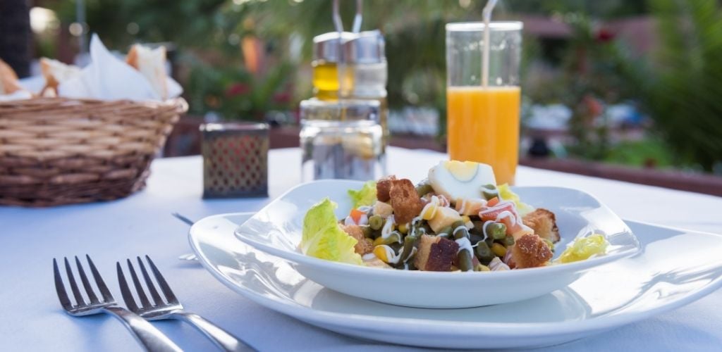 A plate of salad with one glass of juice on the outdoor table. 