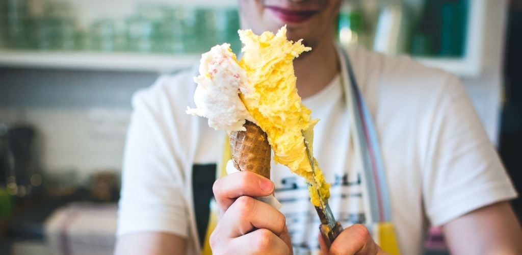 A man preparing a ice cream in a cone. 