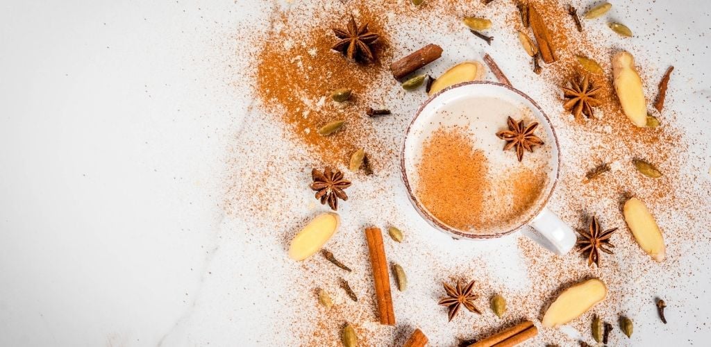 Traditional Indian masala chai tea with spices-cinnamon, cardamon, anise, white background. 