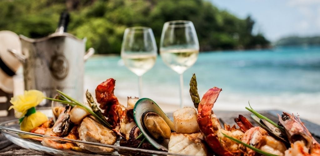 a long plate of seafood and two glass of wine on the sea shore. 