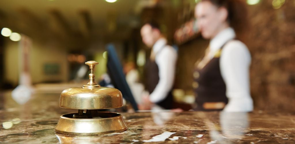 A photo of the hotel reception with the golden bell and staff on the background