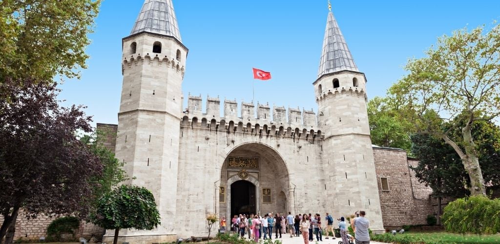 The gate of Topkapı Palace in Istanbul and there are tourists enjoying the view. 