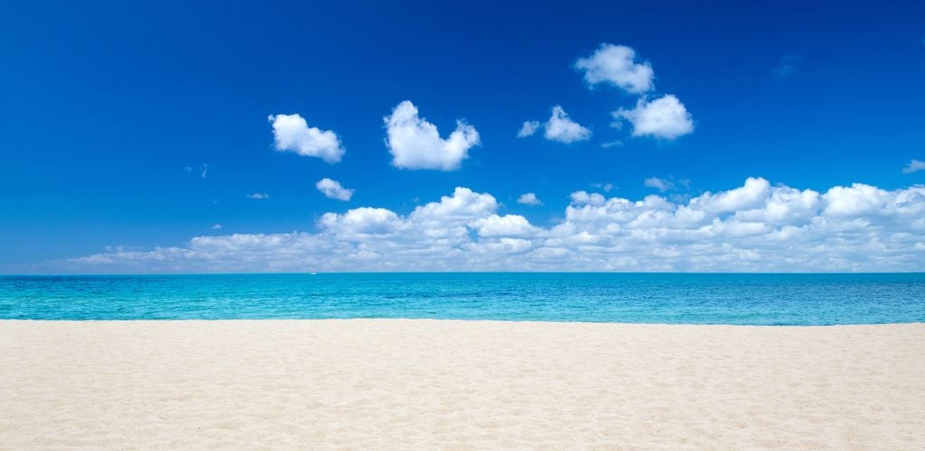 A white beach sand and a calm sea and blue sky. 