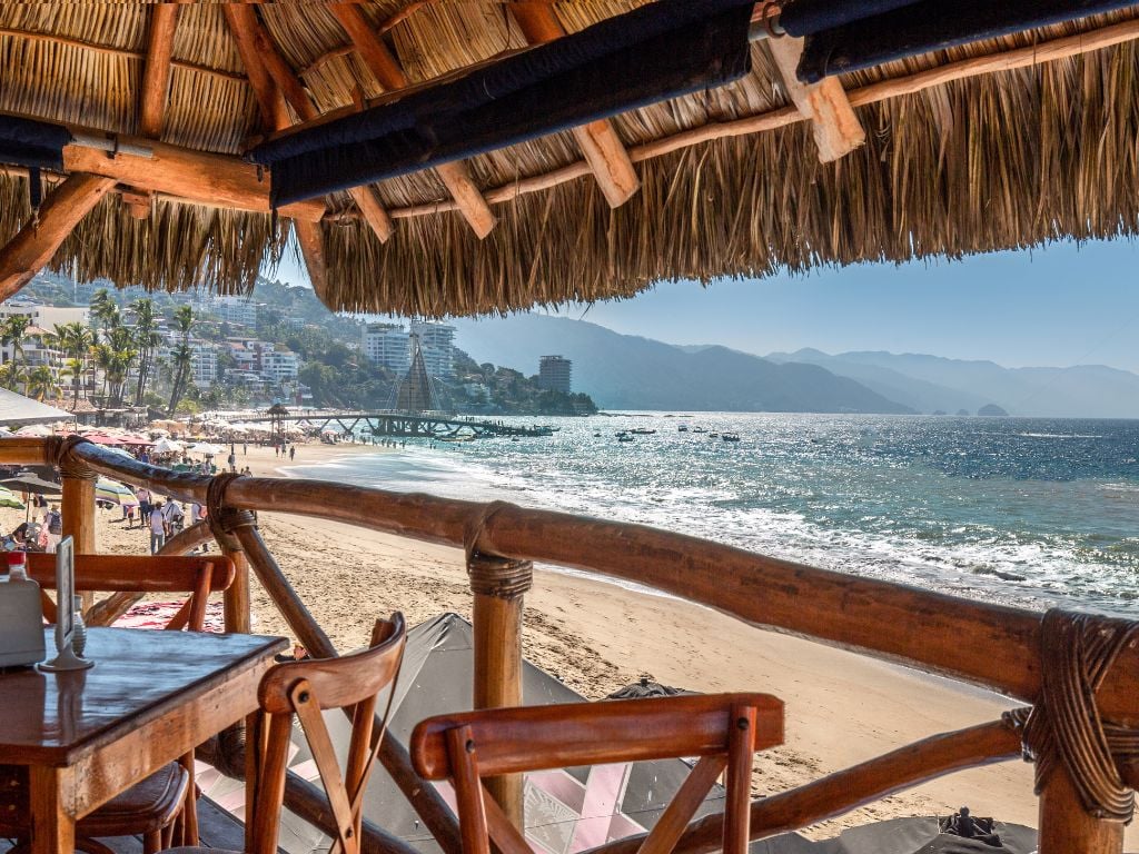 ocean view from restaurant with palm thatching and wooden chairs in puerto vallarta mexico