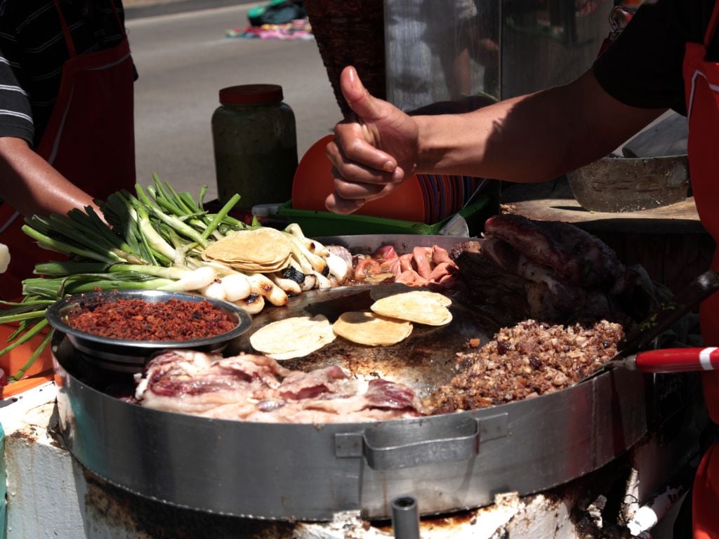 local street food in mexico with grilled onions, ground meat and taco shells