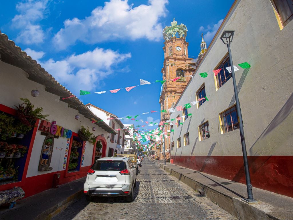 cobbled street in puerto vallarta with colourful flags and church