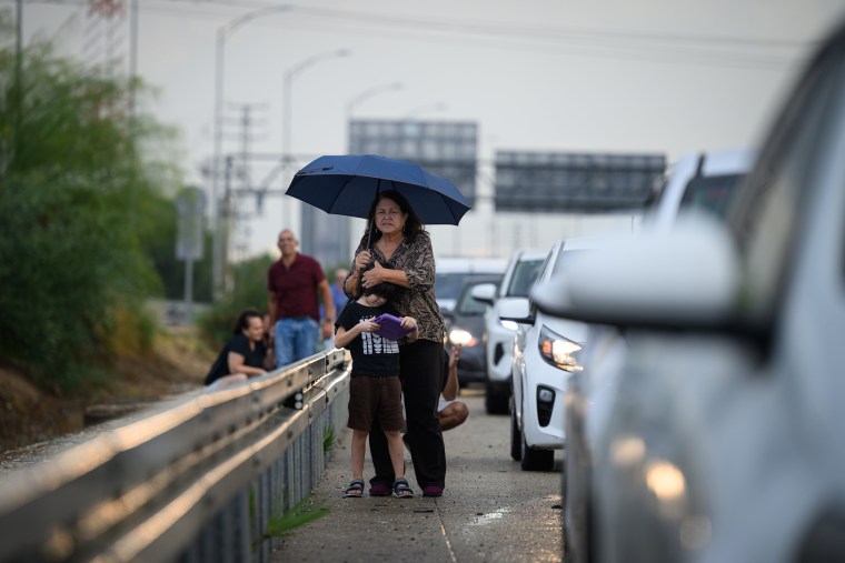 A woman looks for further incoming rockets as she shelters by the side of the road with a young boy on Oct. 16, 2023 in Tel Aviv.