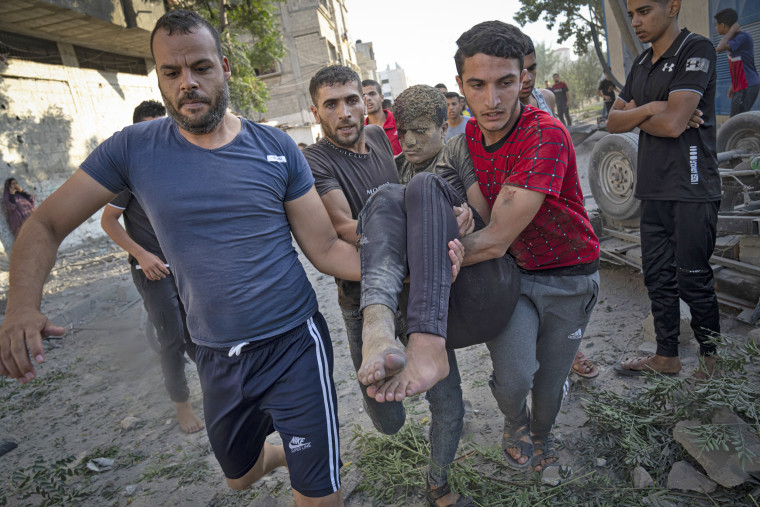 Palestinians carry a person wounded in Israeli airstrikes in Khan Younis, Gaza Strip, Monday, Oct. 16, 2023. 