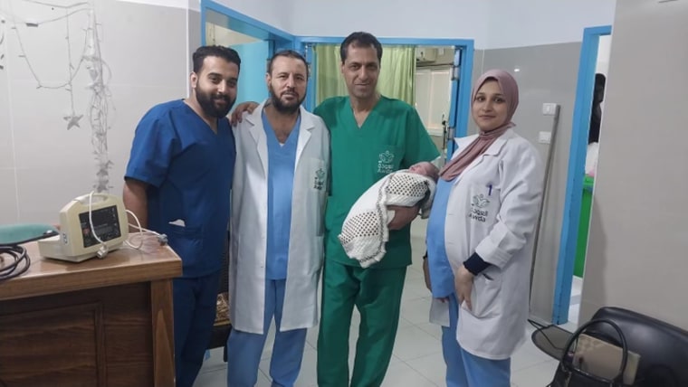 Dr. Ahmed Mhanna, the manager of Al-Awda Hospital, with a baby he and his staff at Al-Awda delivered Sunday.