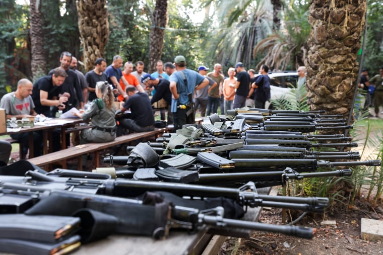 Israelis arrive at a weapons distribution point for people allowed to carry arms at the Ayyelet HaShahar Kibbutz.