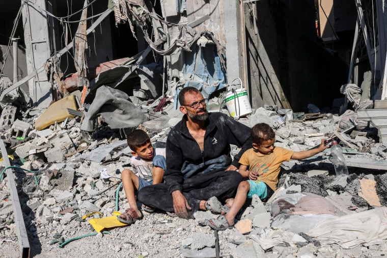 A family sits outside a building destroyed in an Israeli airstrike in Rafah, Gaza.