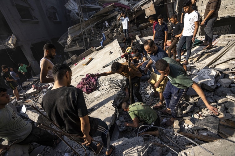 Palestinians search for bodies and survivors in the rubble of a residential building leveled in an Israeli airstrike in Al Shati refugee camp.
