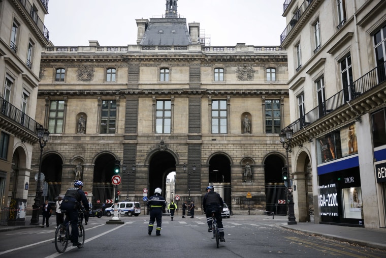 Police officers stand guard outside the Louvre Museum