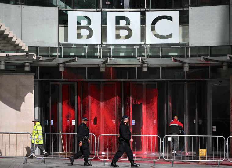 Workmen clean off red paint from the windows at the entrance to the BBC