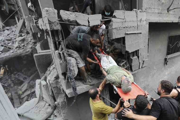 Palestinians carry an injured man out of the destruction following Israeli airstrikes on Gaza City on Oct. 27, 2023.