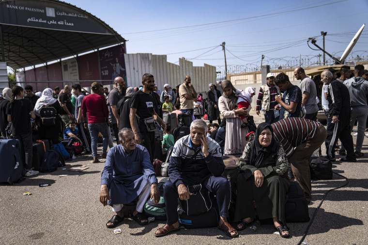 Image: Palestinians wait to cross into Egypt at the Rafah border crossing in the Gaza Strip