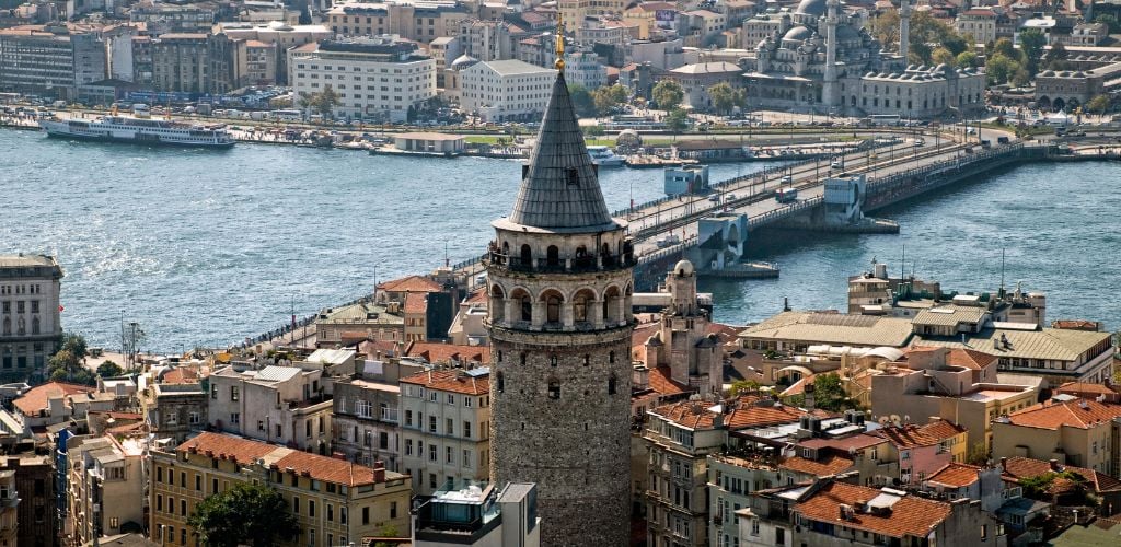 A Galata tower in the background, surrounded by buildings and a gorgeous river. 