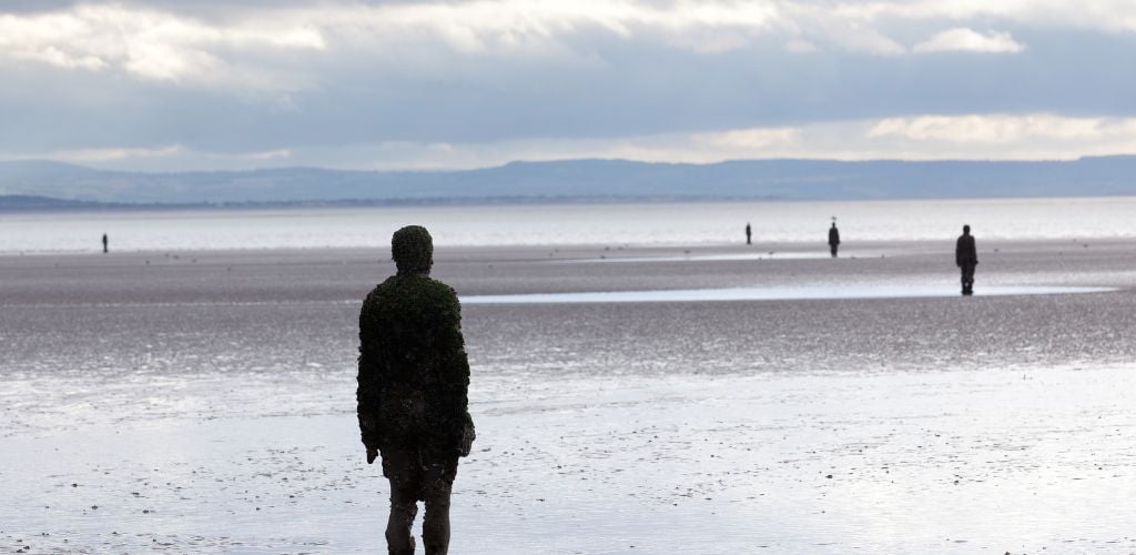 CROSBY BEACH, ENGLAND - SEPTEMBER 24: Statues forming Another Place by Antony Gormley on Crosby Beach on September 24, 2011. The statues are slowly rusting away with the tides and wind.