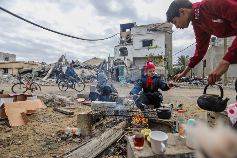 A family gathers around a fire in front of the rubble of their destroyed home in Khan Younis, southern Gaza, on Nov. 28, 2023.