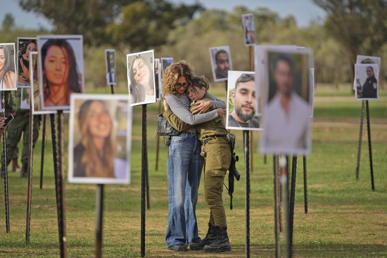 Israelis embrace next to photos of victims of the attack on the Nova music festival displayed at the site, near kibbutz Re'im, on Tuesday, Nov. 28, 2023. 