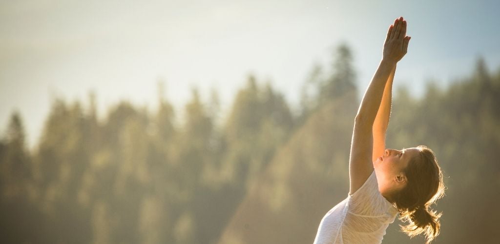 A woman doing yoga under the sunset