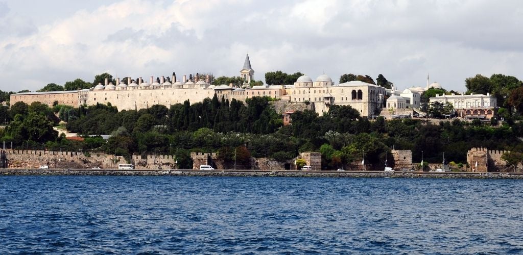 Topkapı Palace surrounded of green trees and sea water. 